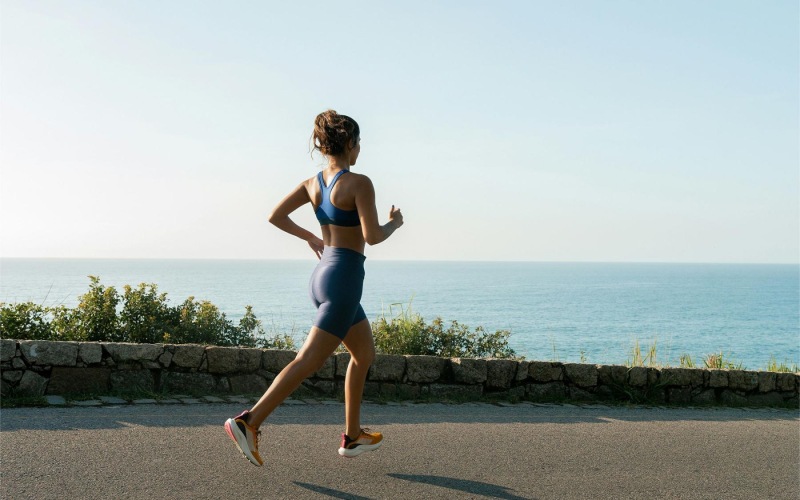 a woman running on a road by the water