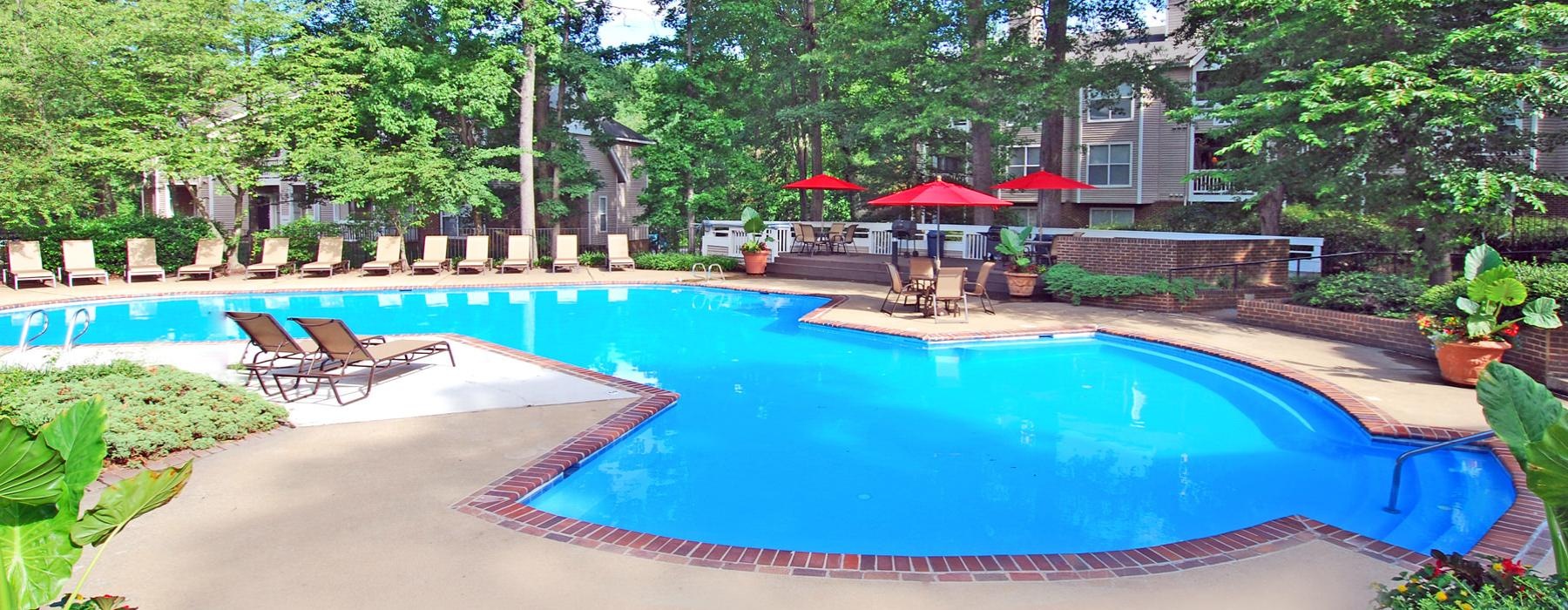 a swimming pool with chairs and umbrellas next to it