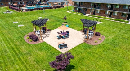 Social area with pergola covered grills and umbrella shaded table and chairs 