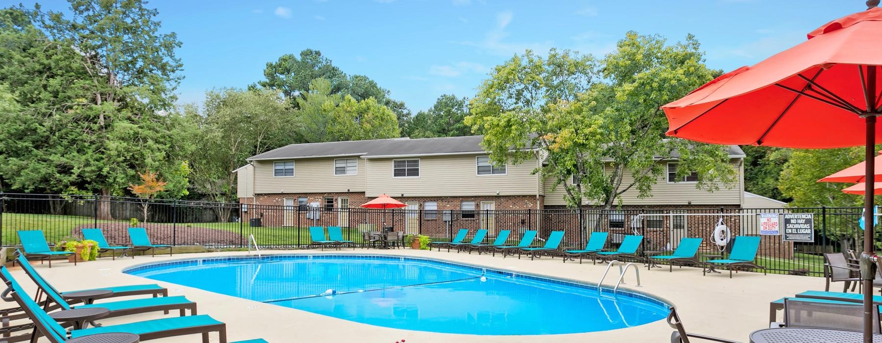 a swimming pool with chairs and umbrellas next to it