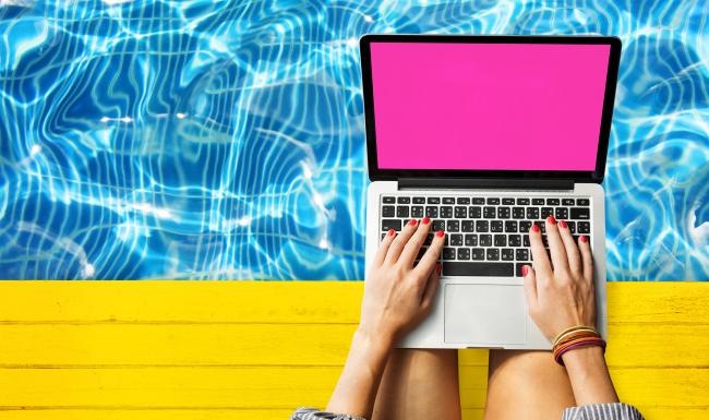 woman sits over pool with laptop on her lap