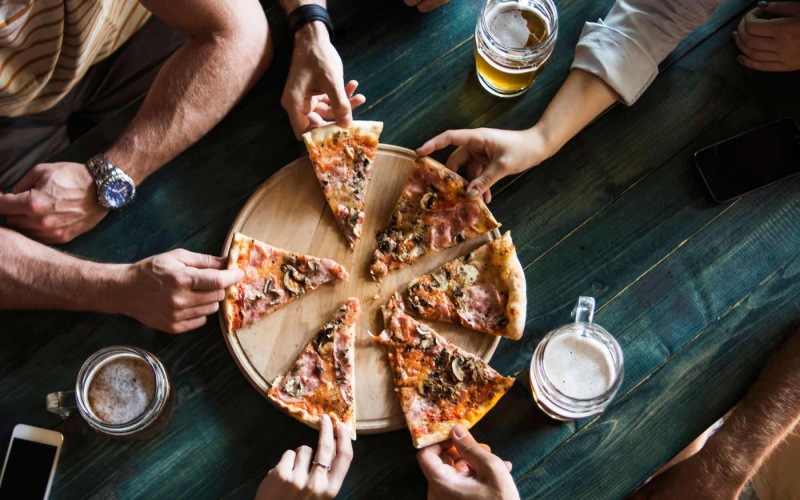 a group of people eating pizza