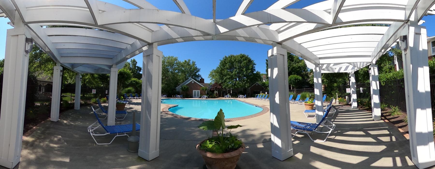a covered patio with chairs and a pool