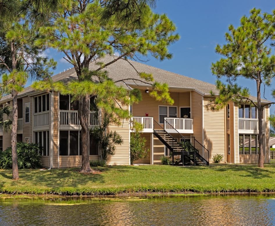 a building with trees and grass near a pond