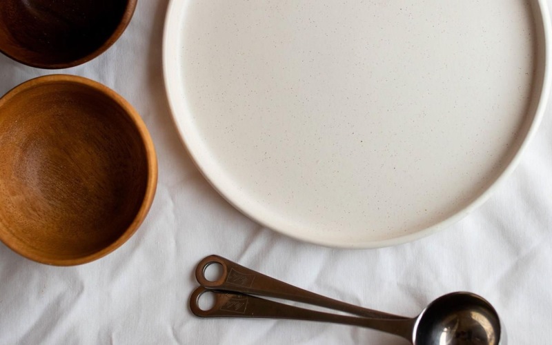 bowls, a plate and measuring spoons arranged neatly on cloth