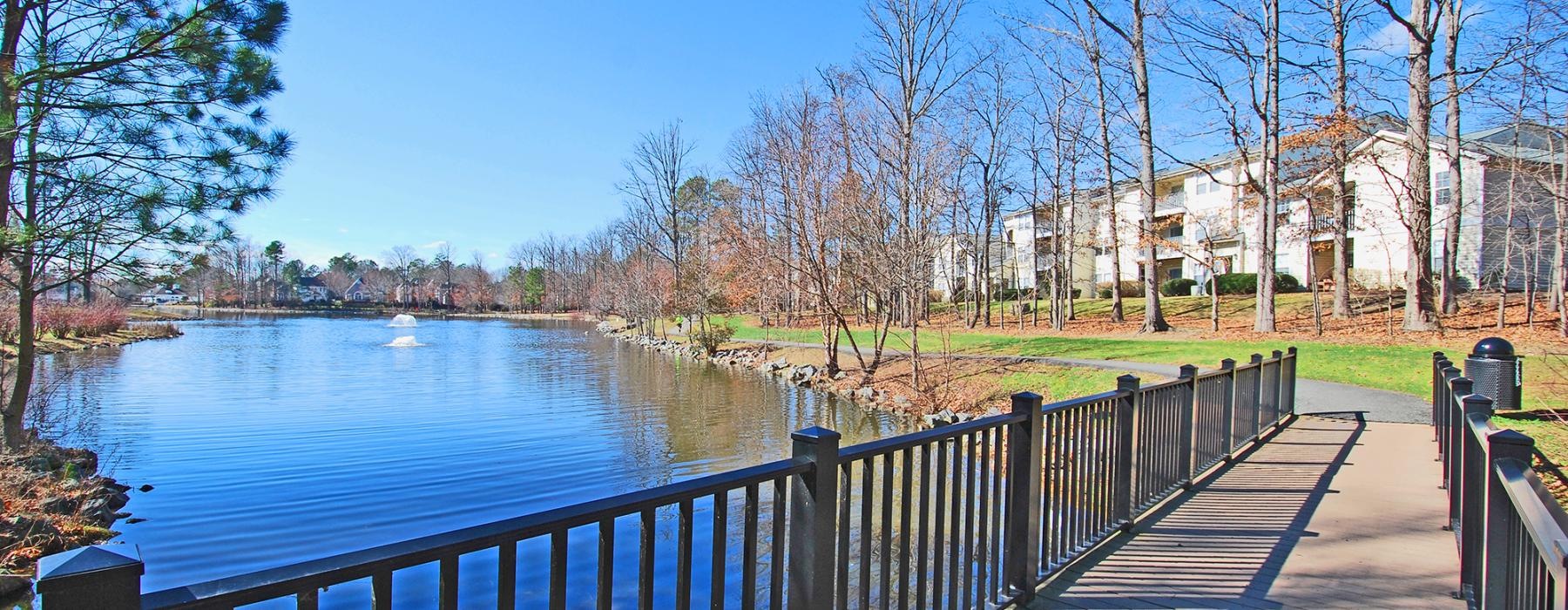 a wooden bridge over a body of water with trees and buildings in the background