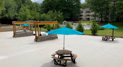 Large social patio with pergolas, umbrellas, and furniture