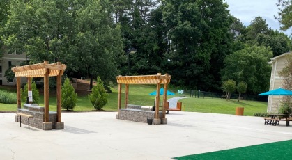 Large social patio with pergolas, grills, umbrellas, and furniture