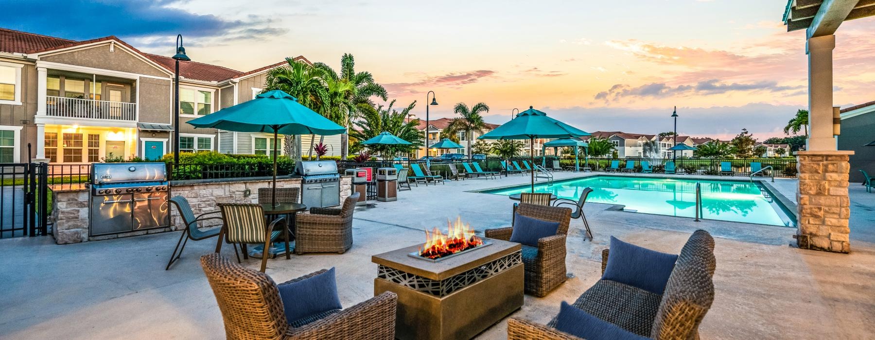 a patio with chairs and tables and umbrellas by a pool