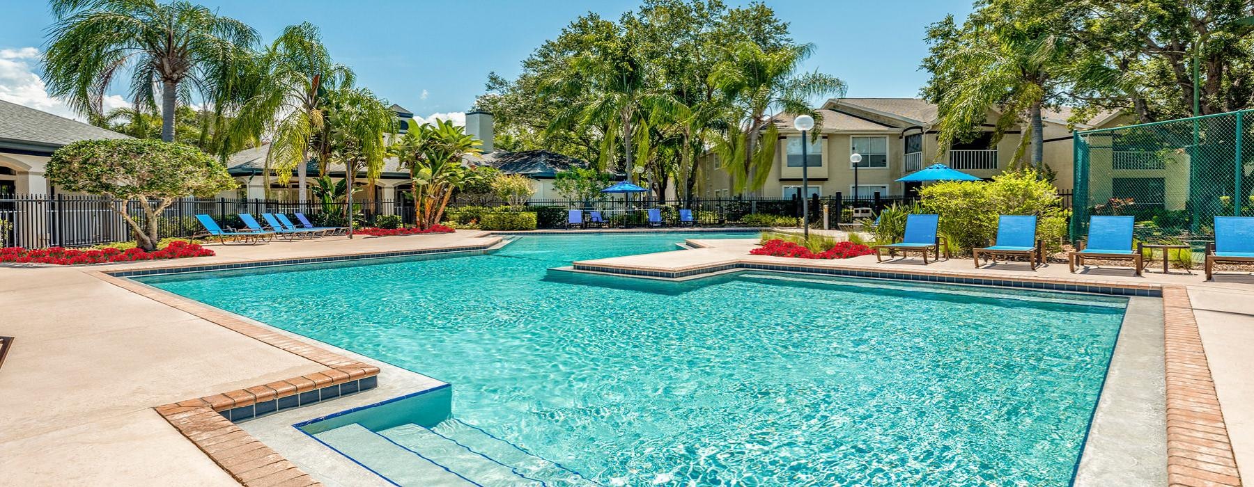 a swimming pool with chairs and umbrellas by a building
