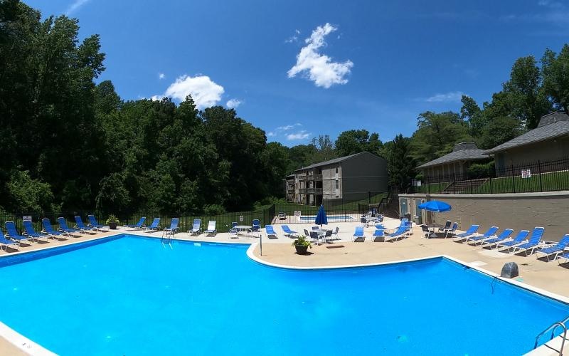 a swimming pool with chairs and umbrellas next to it