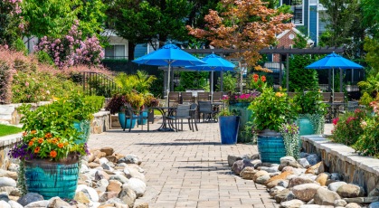 Social area with pergola covered grills and umbrella shaded table and chairs 