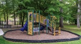 Large trees and beautiful greenery surround the outdoor playground