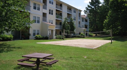 Sand volleyball court next to a picnic table in a grassy field