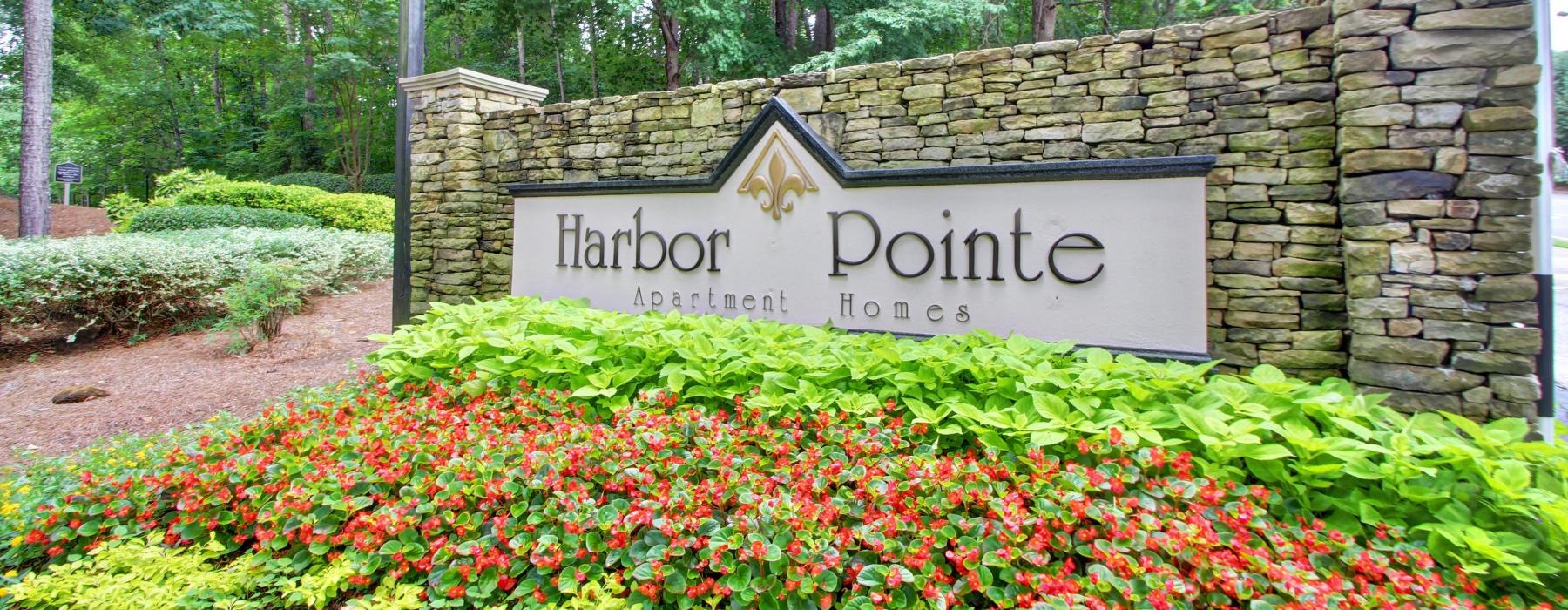 a sign in front of a stone wall with flowers that reads harbor pointe