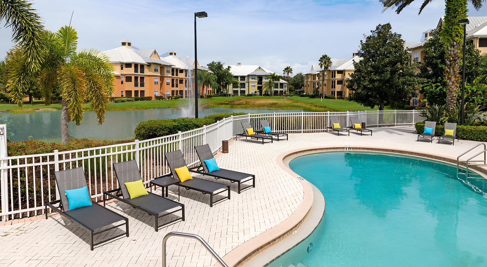 Swimming pool with lounge seating and umbrellas next to lake