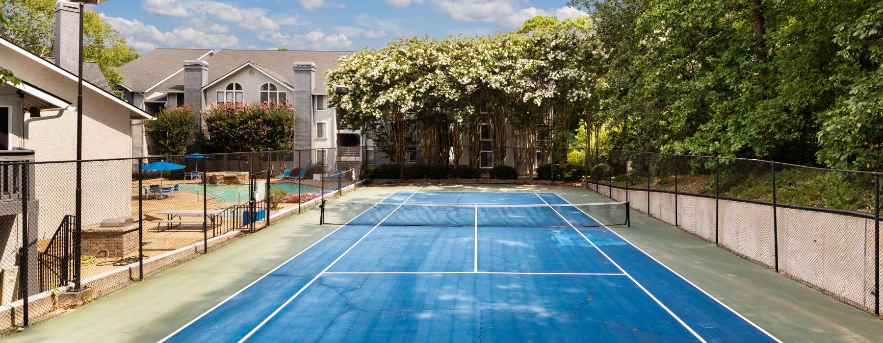 a tennis court with trees and buildings