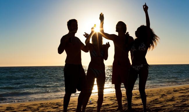 a group of people standing on a beach with their arms raised