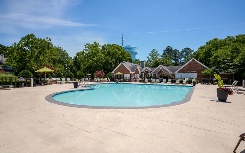 a swimming pool in a courtyard with lounge chairs and a clubhouse