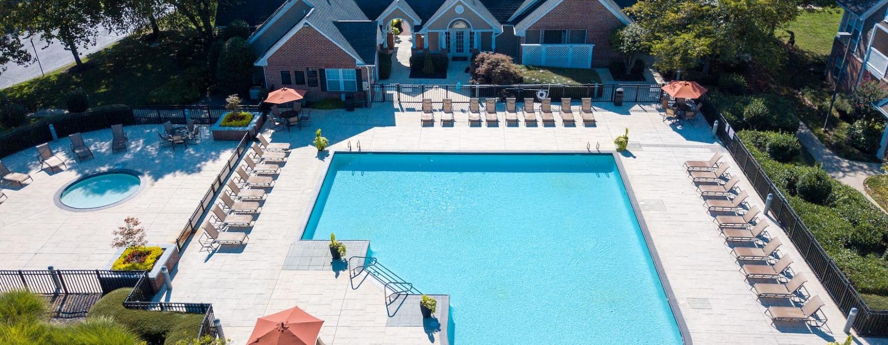 a swimming pool in a courtyard with lounge chairs and a clubhouse