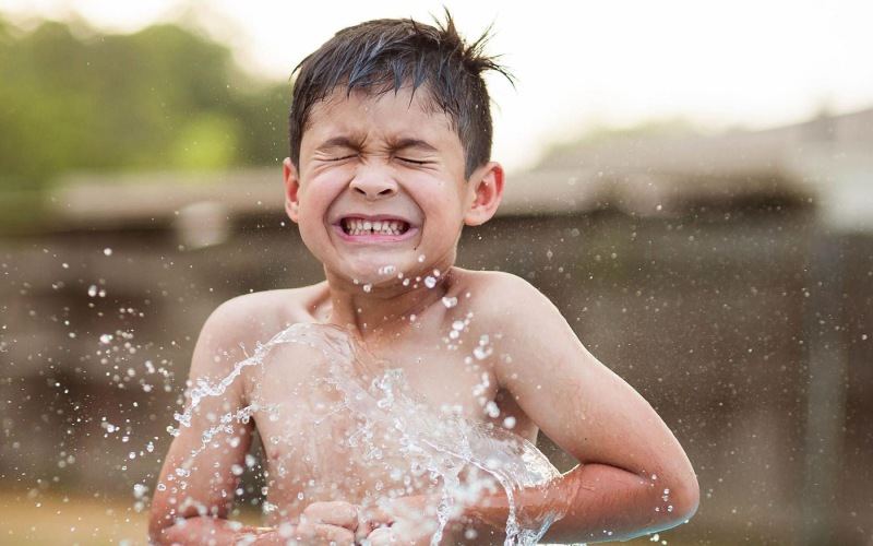 water splashing on a boy in the yard
