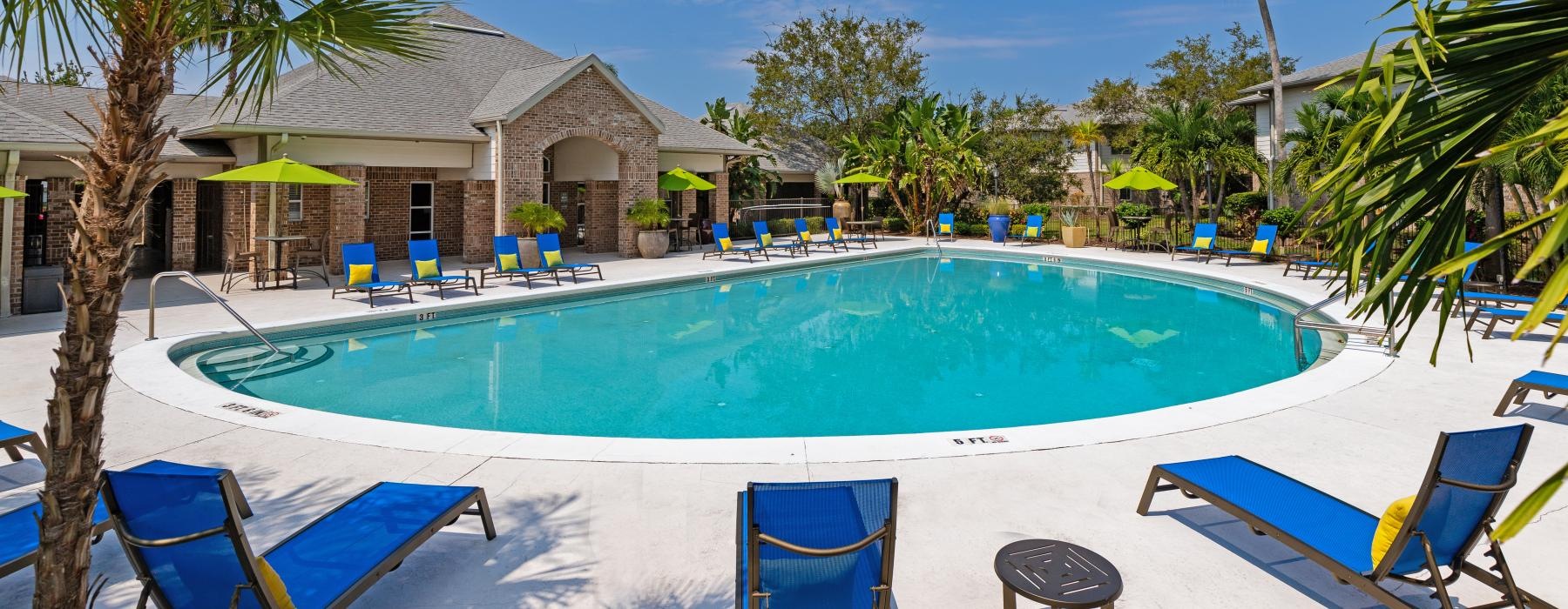 a pool with lounge chairs and trees around it