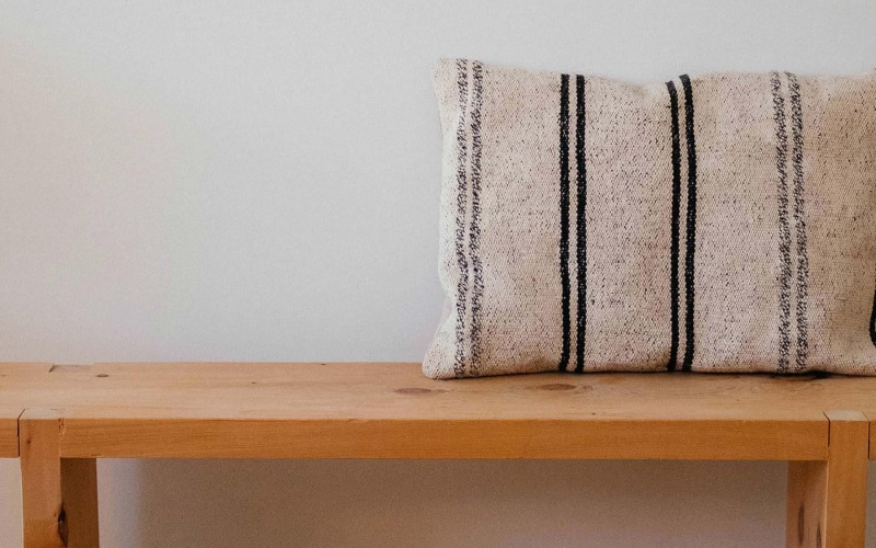 a wooden bench with a striped pillow on it