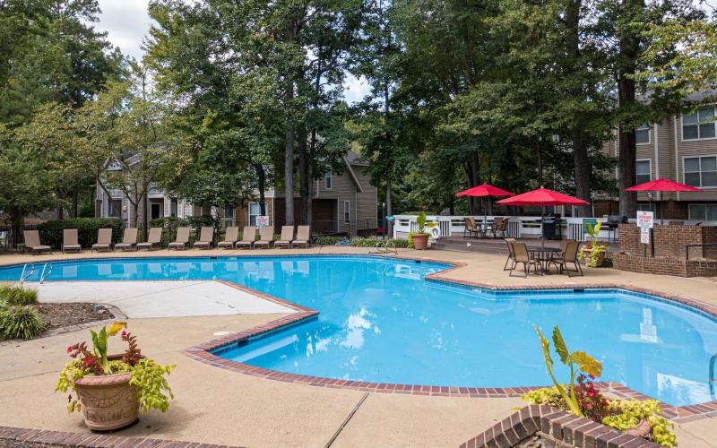a swimming pool with a patio and umbrellas