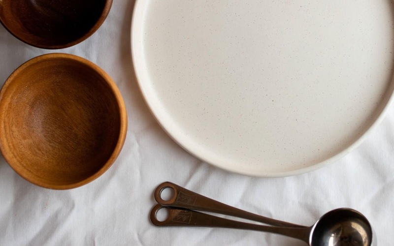 bowls, a plate and measuring spoons arranged neatly on cloth