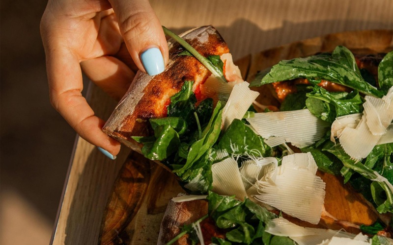 a person holding a slice of pizza