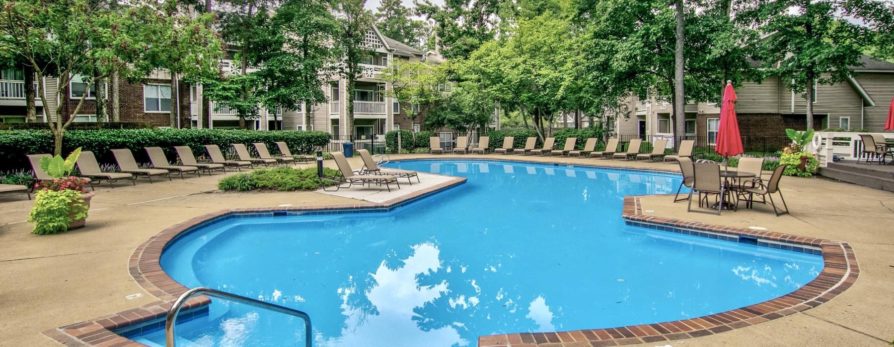 a swimming pool with trees and buildings in the background