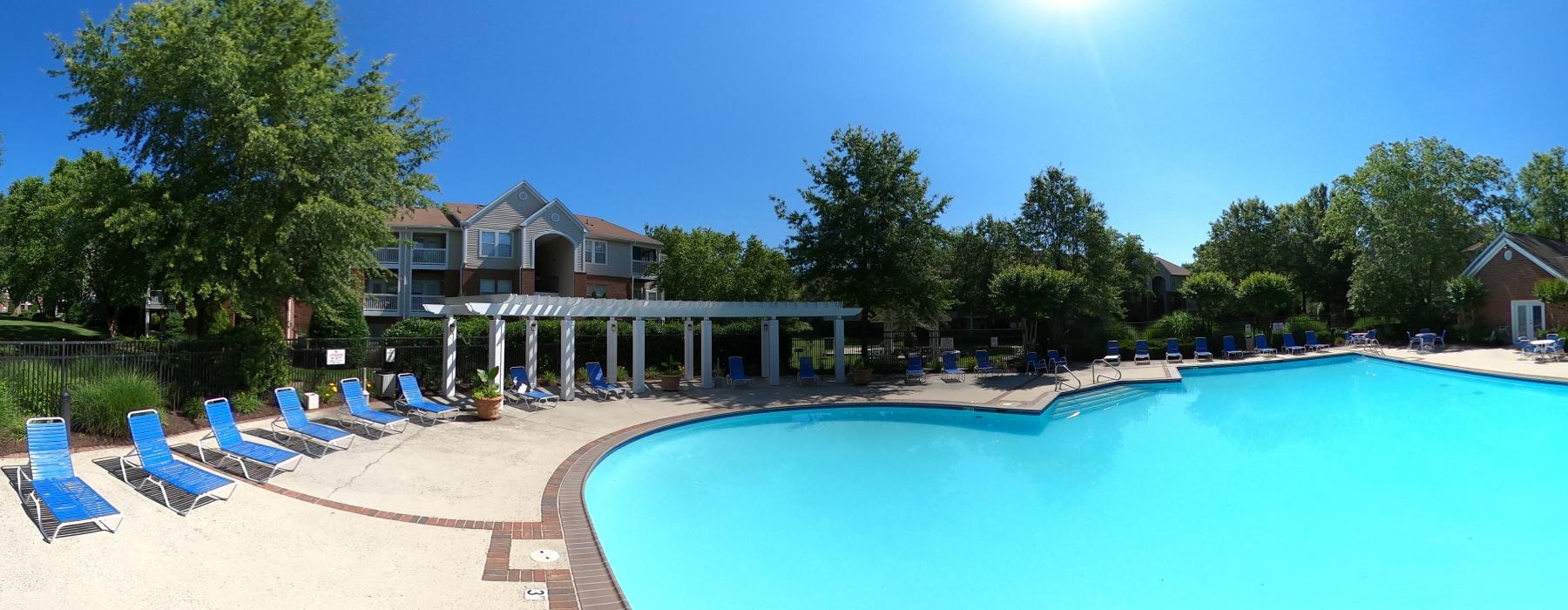 a swimming pool with lounge chairs and trees around it