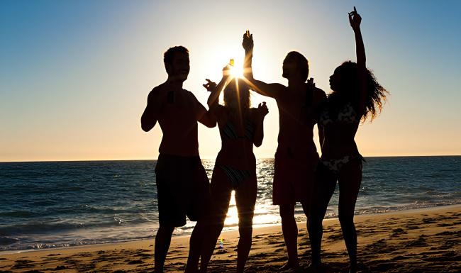 a group of people standing on a beach with their arms raised