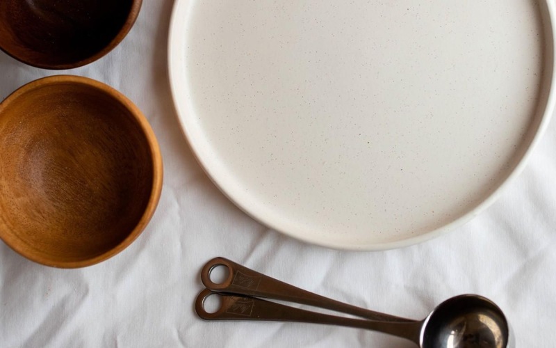 bowls, a plate and measuring spoons arranged neatly on cloth