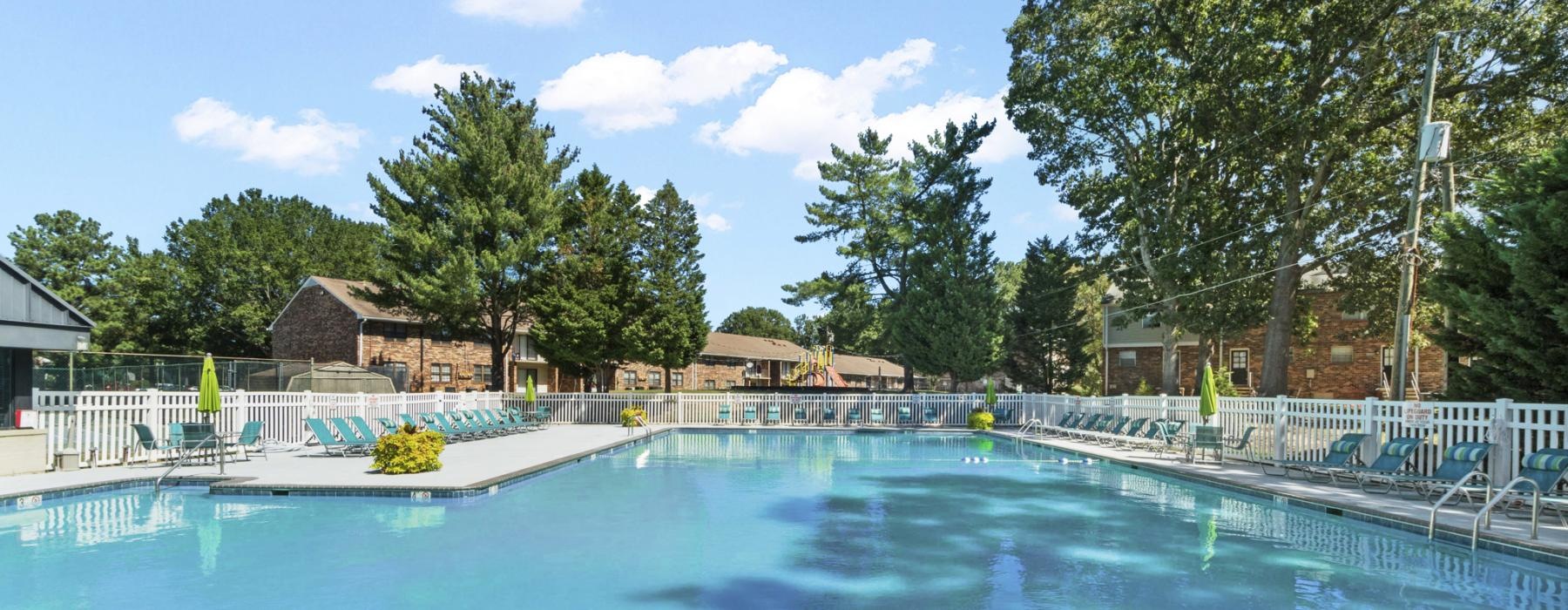 a swimming pool with trees and buildings in the background