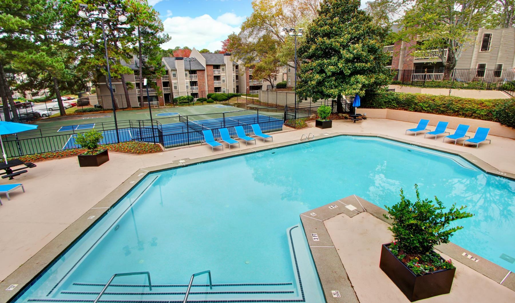 a swimming pool with chairs and trees