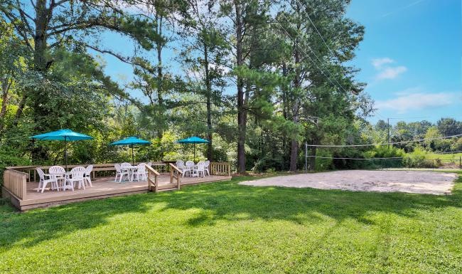 a group of tables and chairs in a grassy area with trees in the background