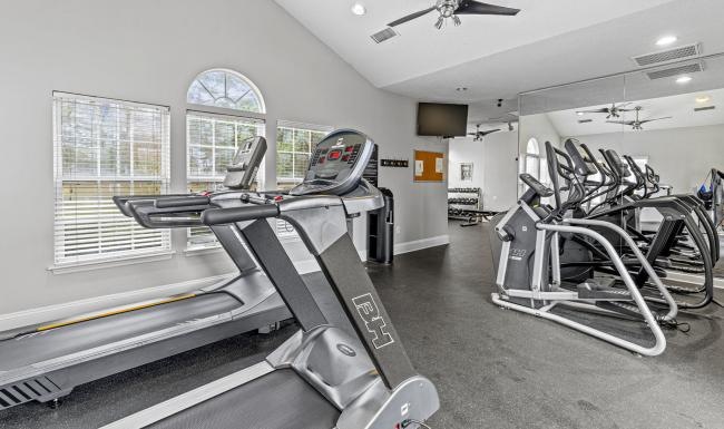 a gym with treadmills and windows