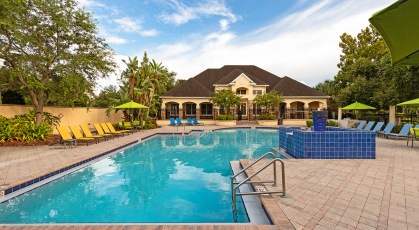 Gated, outdoor pool with adjustable lounge chairs and shaded tables