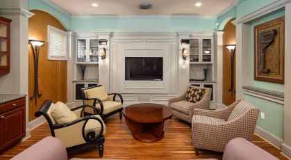 Spacious media room with large tv screen and recessed and sconce lighting