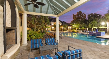 Outdoor fireplace with tables and chairs next to pool area