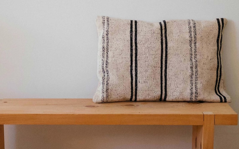 a wooden bench with a striped pillow on it