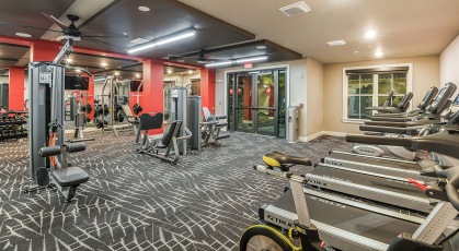Carpeted fitness center with ceiling fans and lighting throughout