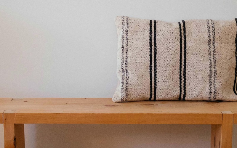 a wooden bench with a striped pillow on it