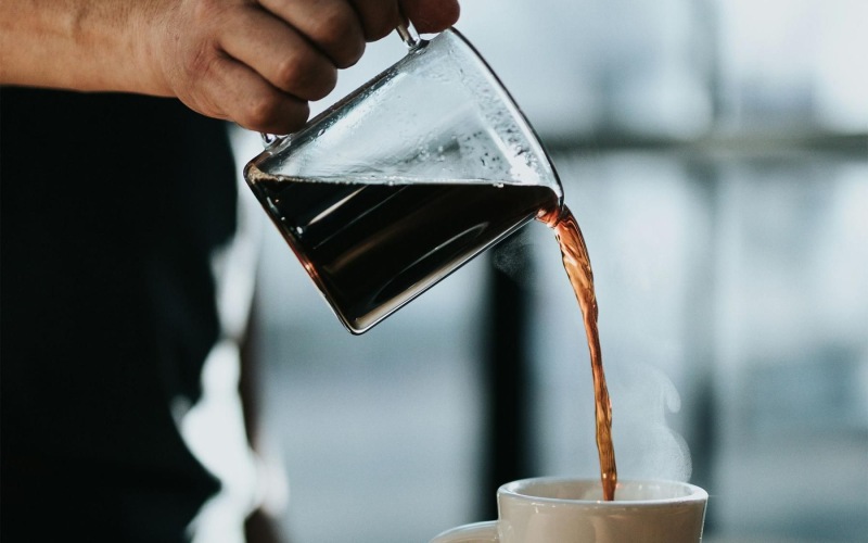 a person pouring a carafe of coffee into a cup