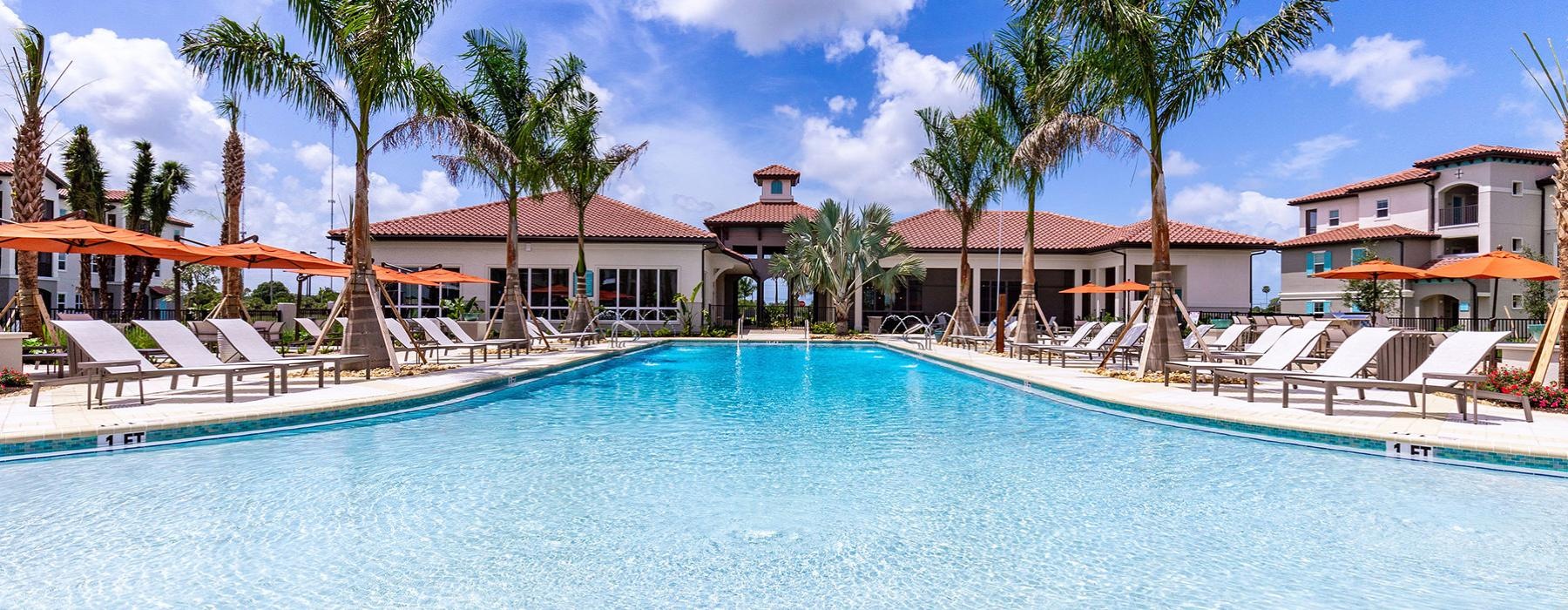 a pool with lounge chairs and palm trees by it