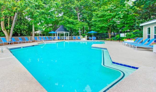 a swimming pool with blue chairs and umbrellas