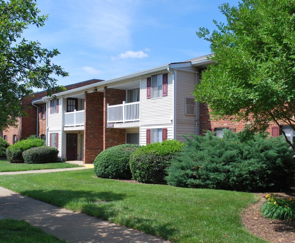 a brick house with a lawn and trees in front of it