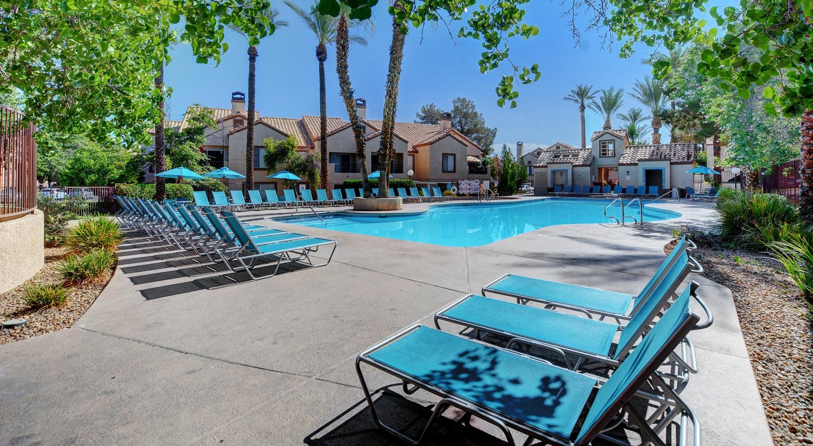 Swimming pool area with palm trees and lounge chairs