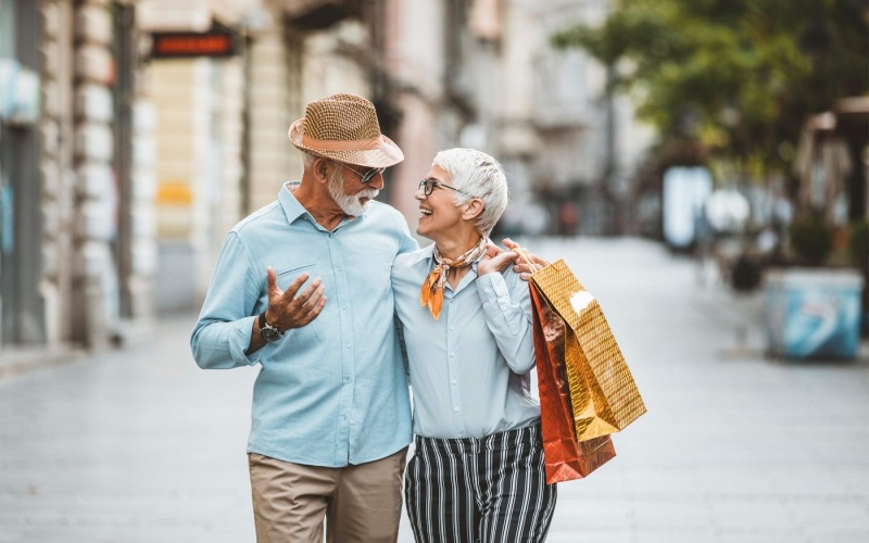 a man and woman holding shopping bags while walking